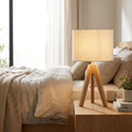 Linnea Tripod Table Lamp with wood legs and linen shade glowing on a nightstand