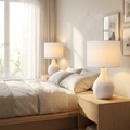 Cova Ceramic Table Lamp Set of two white lamps glowing on bedside tables